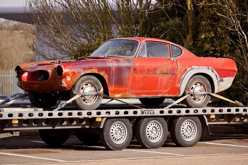 Red car on tow truck that needs work
